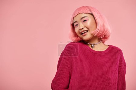 Charmante asiatische junge Frau mit rosa Haaren, die in die Kamera schaut und vor lebendigem Hintergrund lächelt