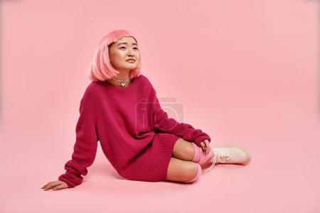 Foto de Hermosa asiática joven chica con rosa pelo y maquillaje sentado y soñando en vibrante fondo - Imagen libre de derechos