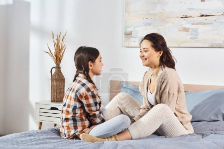 Photo for A moment of serenity as a mother and daughter sit together on a bed, enjoying some quality time together. - Royalty Free Image