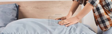 hands of girl rests gently on the pillow, neatly making bed in a warm inviting bedroom.