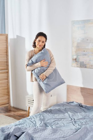 A woman lovingly holds a pillow in a warm, cozy bedroom setting, symbolizing comfort and care between family members.