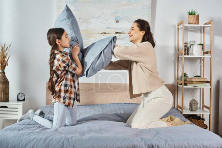 Téléchargez les photos : Une femme et une petite fille jouent joyeusement ensemble sur un lit à la maison, collant et créant des souvenirs chéris. - en image libre de droit