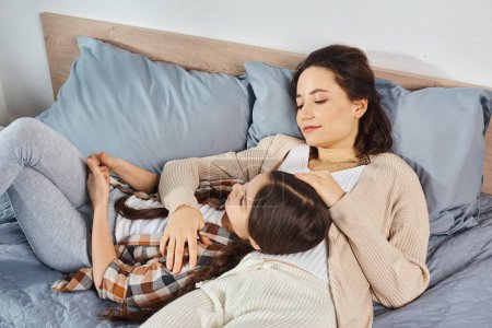 Photo for A mother and daughter relax together on a cozy bed, sharing precious quality time in a quiet, peaceful setting. - Royalty Free Image