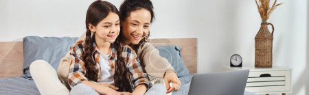 Photo for Mother and daughter, enjoy quality time together on a bed, engrossed in a laptop. - Royalty Free Image
