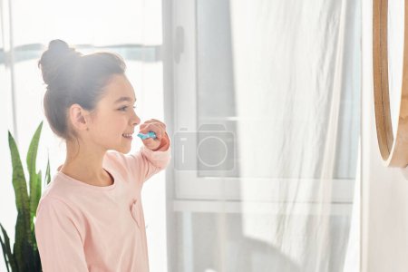 A brunette preteen girl engage in morning beauty and hygiene routine by brushing teeth in front of a mirror.