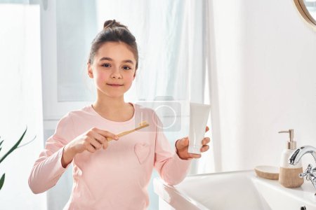 A brunette girl holding a toothbrush in a modern bathroom, emphasizing the importance of hygiene routine.
