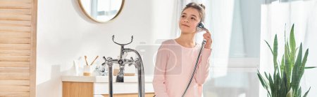 Téléchargez les photos : Une fille brune se tient devant une baignoire dans une salle de bain moderne, bannière - en image libre de droit