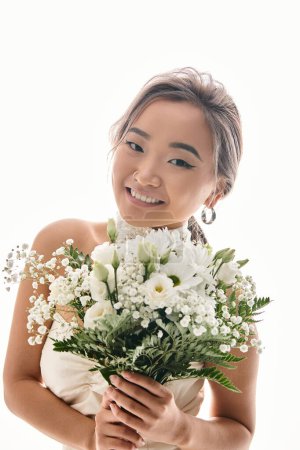 Photo for Happy alluring asian young woman smiling to camera with white flowers bouquet in light background - Royalty Free Image