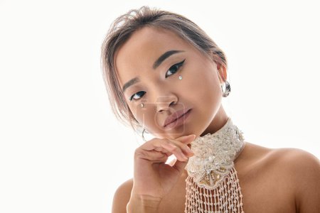 Photo for Attractive asian young woman with elegant makeup tilting head to side and looking to camera - Royalty Free Image