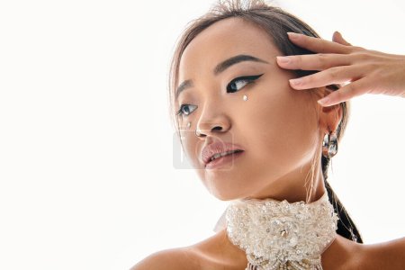 Photo for Portrait of alluring asian young girl with grace makeup posing with hand and looking to side - Royalty Free Image