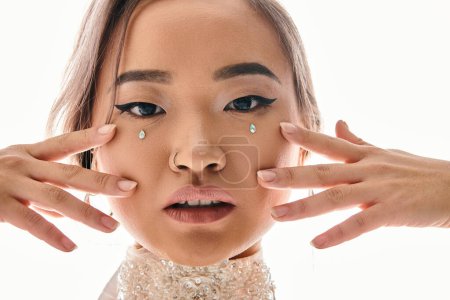 Nahaufnahme einer selbstbewussten asiatischen Frau mit anmutigem Make-up, die vor die Kamera blickt und mit den Händen posiert