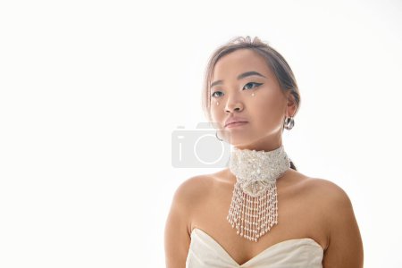 attractive asian young bride in white necklace looking to up on light background