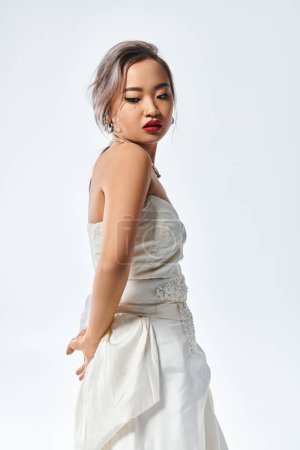 charmante asiatique jeune femme avec rouge à lèvres et collier de perles regardant derrière le dos