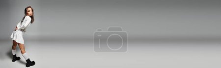Téléchargez les photos : Bannière de mariée non standard avec un maquillage audacieux posant par derrière sur fond gris - en image libre de droit