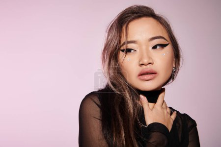 Photo for Attractive asian woman in her 20s with brown hair looking to side and touching to neck with hand - Royalty Free Image