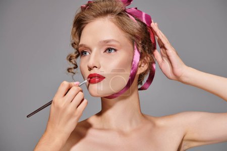 Une jeune femme en studio applique du rouge à lèvres sur ses lèvres, en mettant l'accent sur l'amélioration de sa beauté naturelle.
