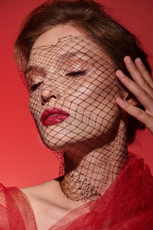 A young woman exuding classic beauty in a stunning red dress, with a veil gracefully covering her head. Poster 698523862