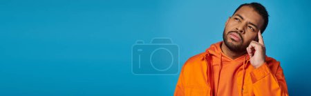 Photo for Banner of thoughtful african american guy in 20s touching to temple with finger on blue background - Royalty Free Image