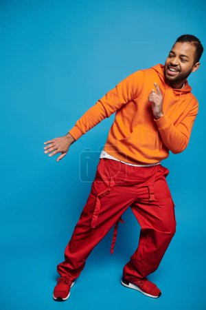 Foto de Atractivo hombre afroamericano en traje vibrante poner el dedo y inclinarse a un lado - Imagen libre de derechos