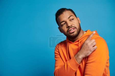 Foto de Encantador hombre afroamericano en traje vibrante mirando a un lado y mostrando el dedo sobre el hombro - Imagen libre de derechos