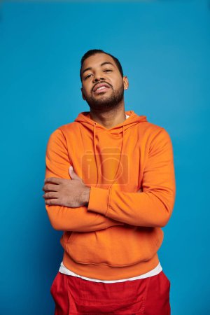 confident african american man posing with folded cross arms against blue background