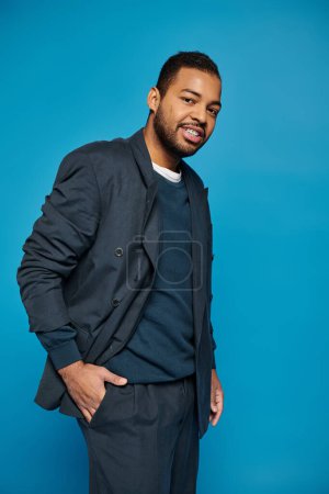 handsome african american man standing to sideways and looking to camera with hand in pocket