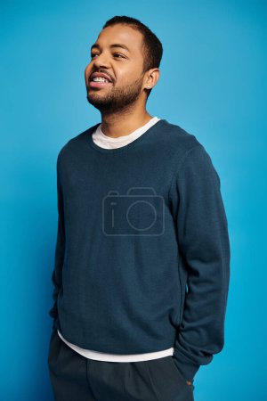 Foto de Sonriente hombre afroamericano de unos 20 años parado con las manos en los bolsillos y mirando al costado - Imagen libre de derechos