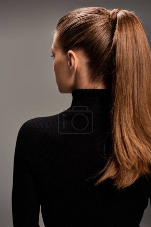 A young beautiful woman with long hair styled in a ponytail, radiating grace and style.