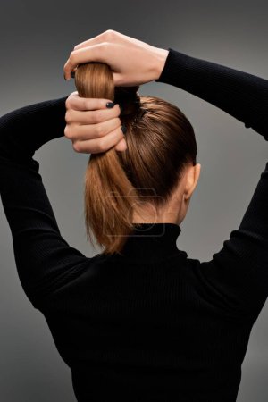 Photo for Back view, young woman with long hair tied in a ponytail exudes beauty and elegance. - Royalty Free Image