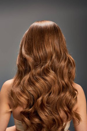 The back of a womans head featuring beautiful, long, wavy hair cascading down effortlessly.