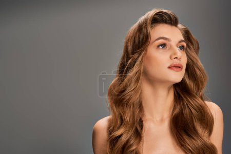 Photo for A young woman with long, wavy brown hair gazes upwards in a moment of contemplation and wonder. - Royalty Free Image