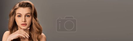 Photo for A young woman with stunning long wavy hair strikes a pose for the camera in a serene and elegant manner, banner. - Royalty Free Image