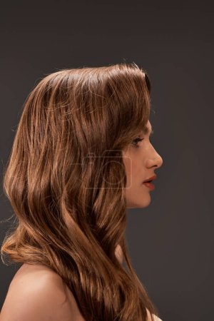 Foto de Un retrato cautivador de una joven con cabello castaño hermoso y largo y flequillo, exudando un aire de misterio y encanto. - Imagen libre de derechos