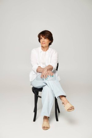 Full length shot of mature beautiful woman sitting with her arms crossed and looking at camera