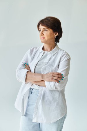 Portrait of mature beautiful woman standing with her arms crossed and looking away