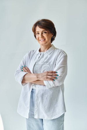 Middle aged cheerful woman standing with her arms crossed and looking at camera with smile