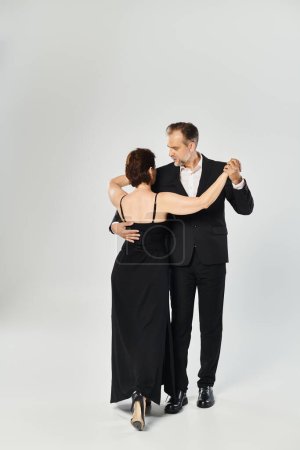 Ballroom dance middle aged couple in a dance pose and smiling isolated on grey background