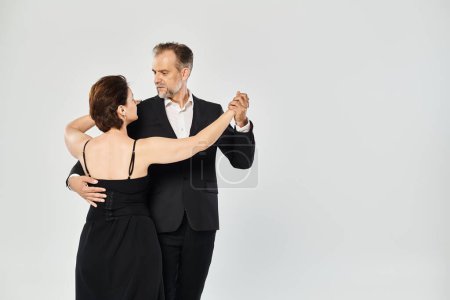 Porträt eines attraktiven Paares mittleren Alters in einer Tangotanzpose isoliert auf grauem Hintergrund