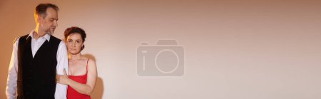 Téléchargez les photos : Couple mature debout et câlin dans des tenues élégantes avec lumière jaune sur fond gris, bannière - en image libre de droit
