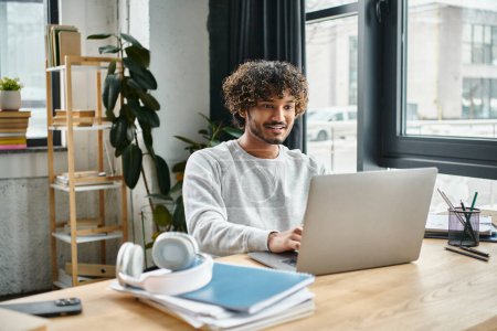 Ein Mann mit unterschiedlichen kulturellen Hintergründen sitzt an einem Laptop in einem Coworking Space, konzentriert und mit seiner digitalen Arbeit beschäftigt.