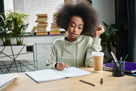 Una mujer, inmersa en el pensamiento, se sienta a una mesa escribiendo sobre un pedazo de papel en un moderno espacio de coworking.