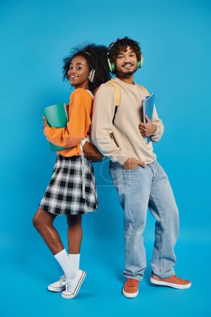An interracial couple, students in casual attire, stand together in unity against a blue backdrop.
