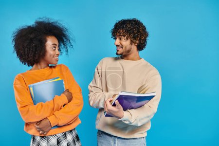 Téléchargez les photos : Deux étudiants interraciaux se tiennent côte à côte sur un fond bleu, symbolisant l'unité et la diversité. - en image libre de droit
