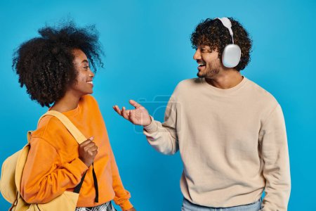 Dos estudiantes interraciales que usan atuendos casuales se paran juntos con confianza contra un telón de fondo azul en un ambiente de estudio.