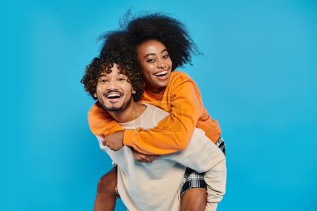 Photo for An interracial couple of students in casual attire standing together, with the man supporting the woman on his back. - Royalty Free Image