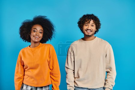 Téléchargez les photos : Deux étudiants interraciaux en tenue décontractée côte à côte sur fond bleu dans un décor studio. - en image libre de droit