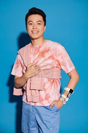 Ein modischer junger Mann in trendiger Kleidung posiert vor einer auffallend blauen Wand.