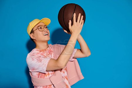 Photo for A stylish woman in a yellow hat confidently holds a basketball, exuding energy and strength against a vibrant backdrop. - Royalty Free Image