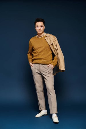 A fashionable young man poses confidently in a tan sweater and khaki pants, exuding elegance and style.