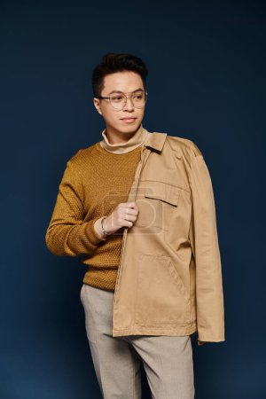 A fashionable young man posing actively in a brown sweater and tan pants.